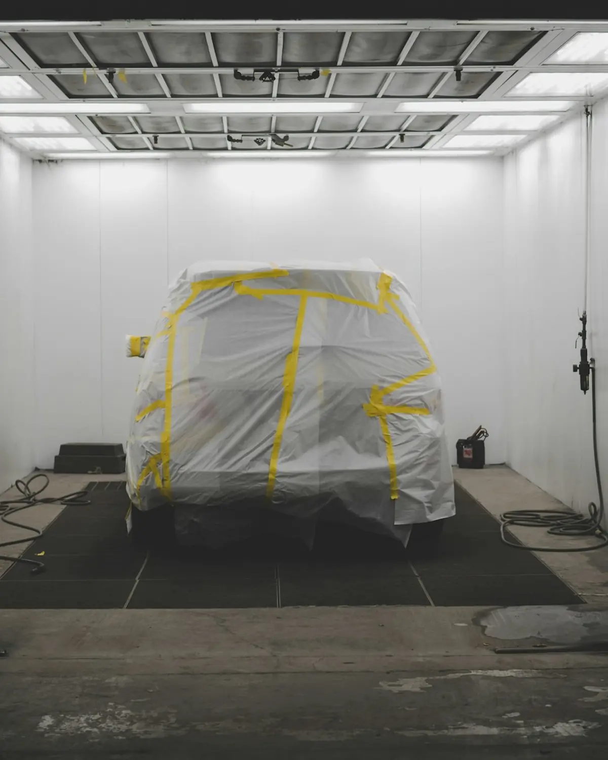 Masked car standing alone in a dimly lit spray booth