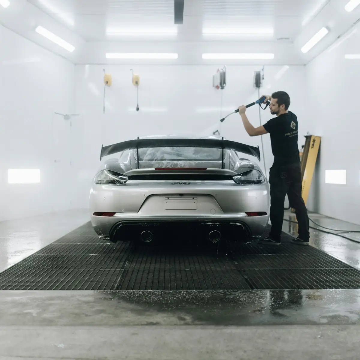 Masked car being prepared for paint inside a workshop bay
