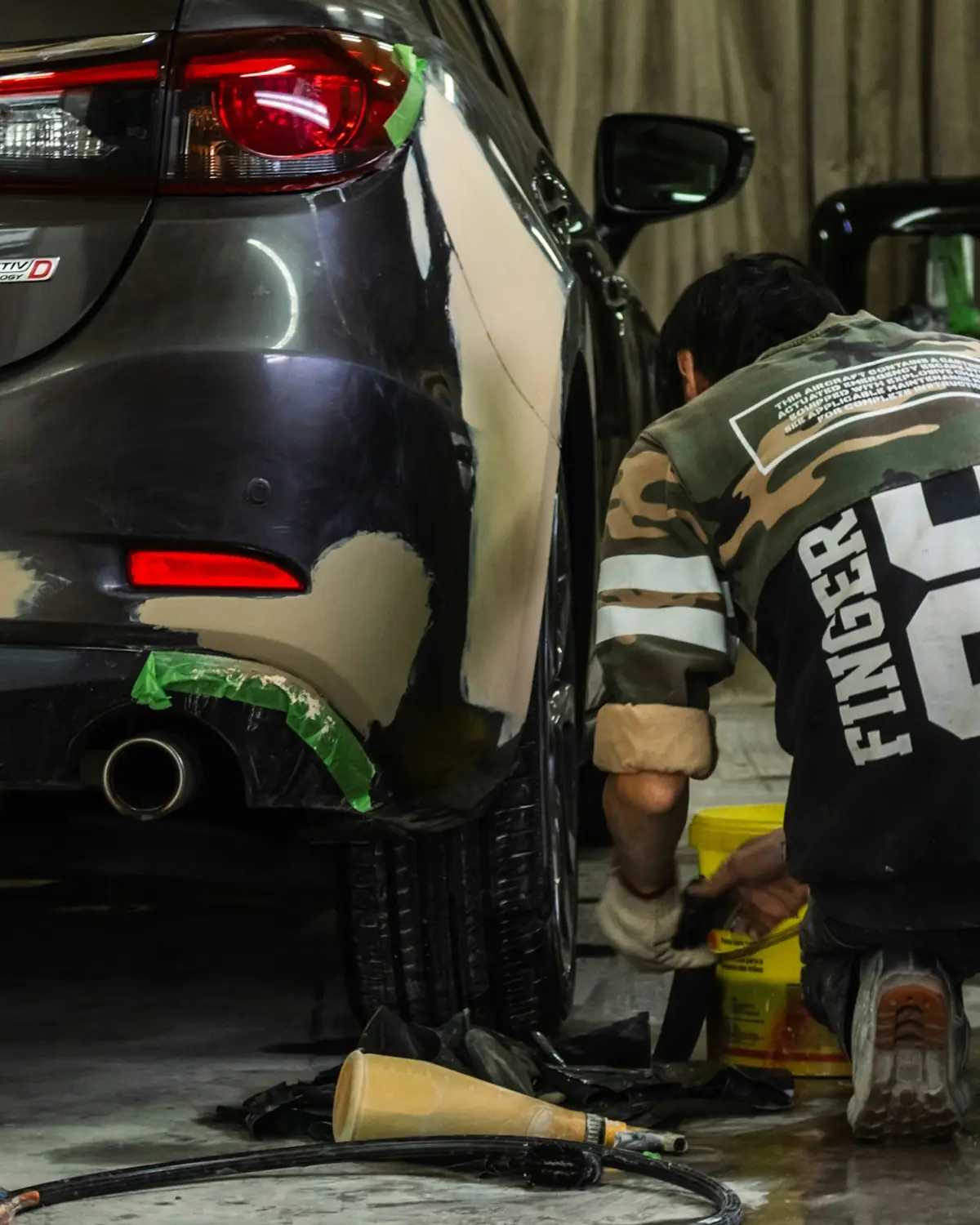 Repairer working a rear bumper back into shape in a workshop