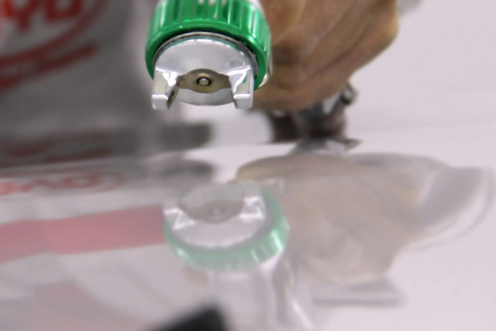 Spray gun laying a wet coat of paint across a car panel